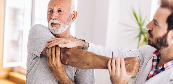 Elderly man receiving shoulder adjustment from Akron chiropractor